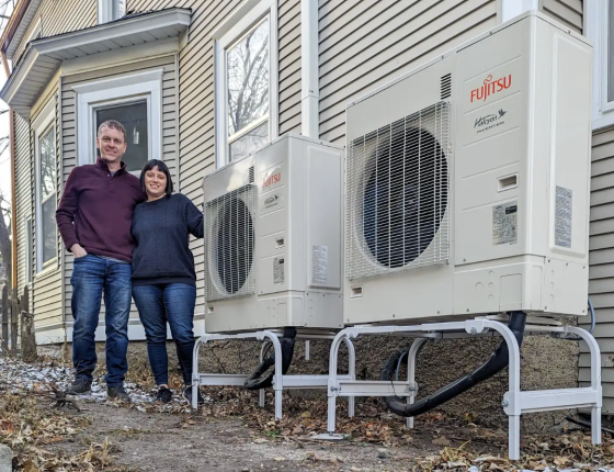 couple standing beside new heat pump units