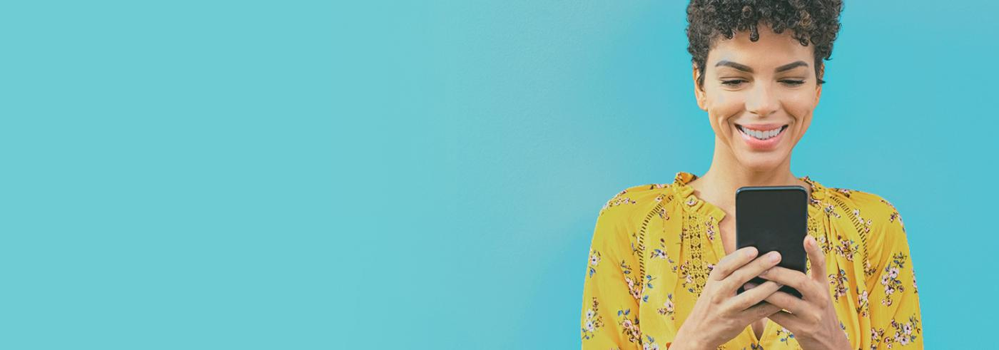 A woman in a yellow shirt on a phone against a blue background.